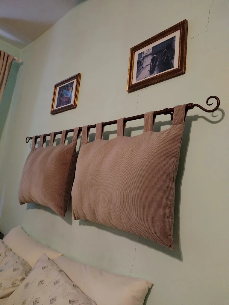 A bedroom with cushions hung from an iron rail