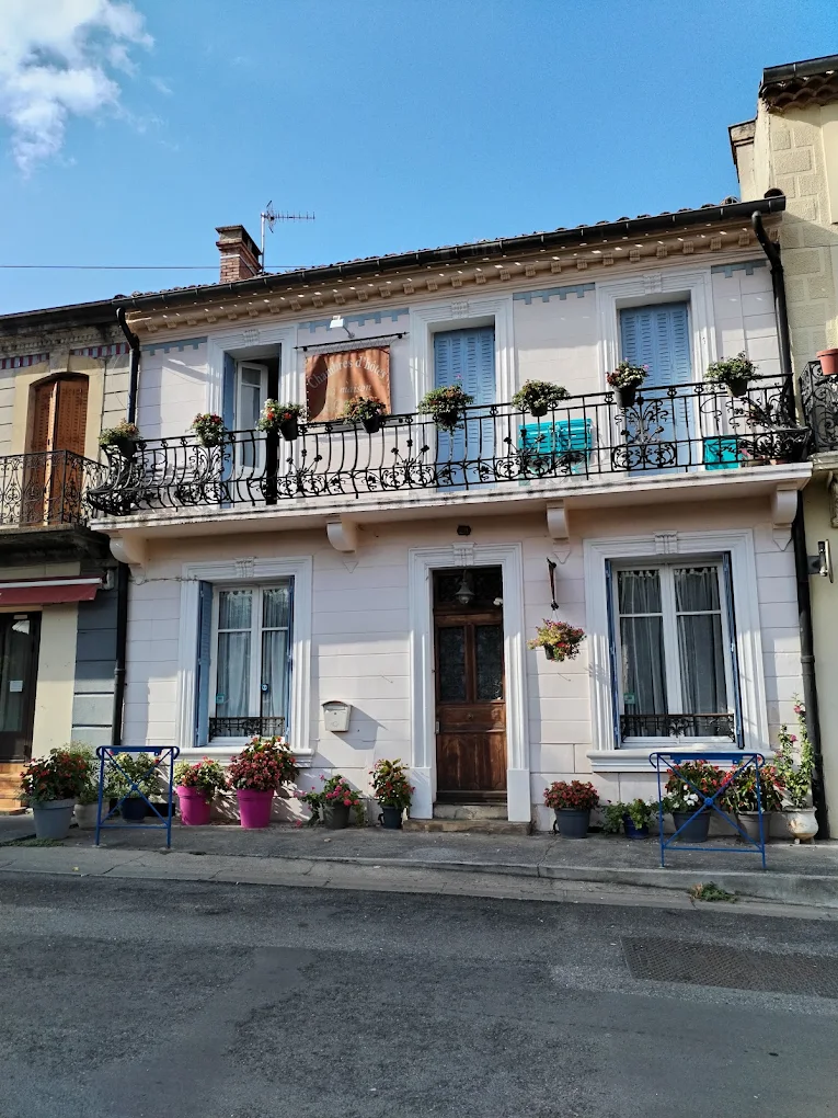 The front of La Maison de la Rivière with blue shutters and an iron balcony